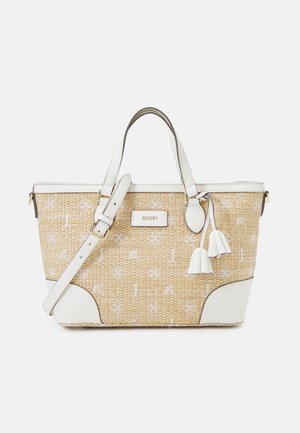 Sac en toile tressée avec des accents en cuir blanc, arborant un logo doré, des pampilles décoratives et une forme structurée. Sangle d'épaule réglable incluse.
