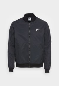 Zwarte nylon bomberjack met een ritssluiting aan de voorkant, zijzakken, geribbelde manchetten en een wit Nike-logo op het linkerborstgebied.