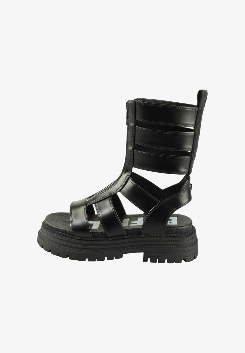 Črne platformne sandale z zaprtim nosom, odprtimi stranmi, več trakovi in teksturiranim podplatom. Vsebujejo zadrgo in blagovno znamko na notranji podplati.