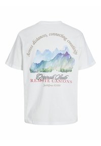 Balta kokvilnas T krekls ar kalnu akvareļa druku uz aizmugures, virs uzraksta "Pāri attālumiem, savieno radošumu" atrodas "REMOTE CANYONS."