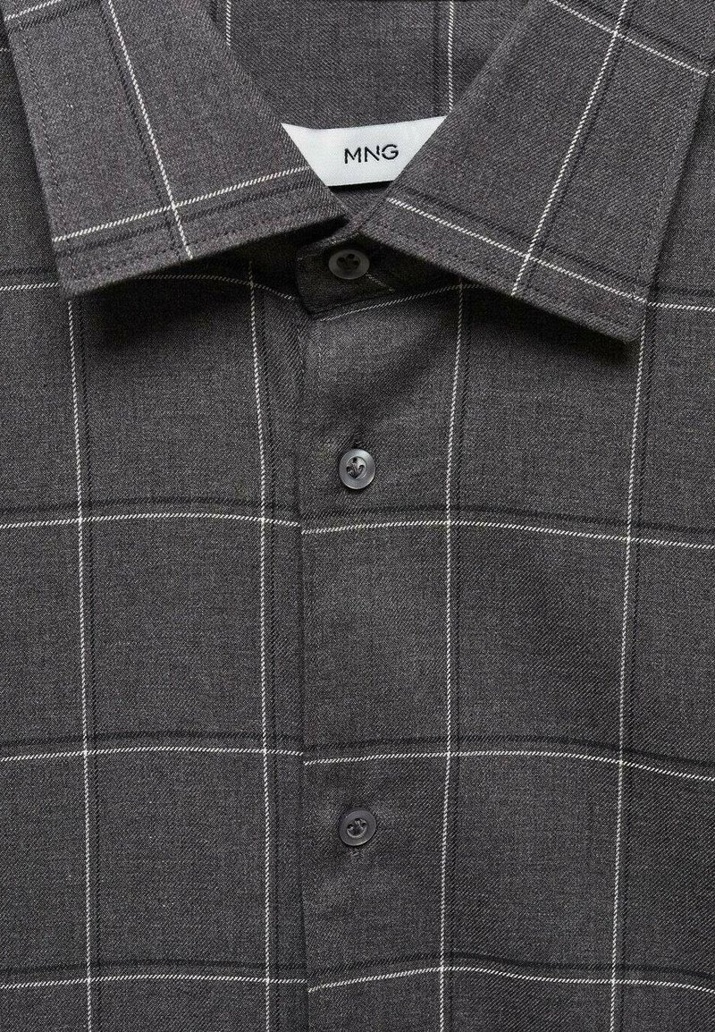 Grau karierter Button-Up-Hemd mit Kragen, das weiße Gitterlinien und dunkle Knöpfe aufweist. Der Stoff hat eine strukturierte Optik. Markenlabel sichtbar.