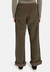 Pantalons à carreaux verts avec une coupe décontractée, en tissu doux, jambes larges et ourlets retroussés. Motif texturé avec des accents rouge foncé.