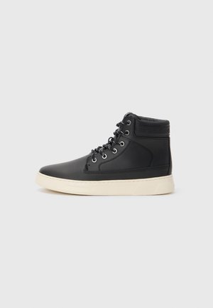 Black high-top sneaker made of smooth leather with a white rubber sole. Features metal eyelets and textured accents along the ankle.