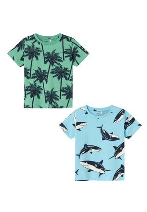 Zwei kurzärmelige T-Shirts: eines in Grün mit schwarzem Palmenprint, das andere in Hellblau mit schwarzen Hai-Mustern, beide aus Baumwollstoff.