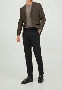 Hnědý károvaný blejzr s klopami, kombinovaný se šedým přiléhavým svetr a černými slim-fit kalhotami. Černé společenské boty dotvářejí vzhled.