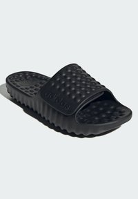 Sorte skridsandaler med en tekstureret overdel med hævede prikker, polstret sål og et ribbet mønster langs siderne. Brandlogo synligt.