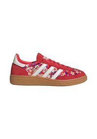 Zapatilla roja de Adidas con franjas blancas, suela de goma y un patrón floral multicolor en los paneles laterales.