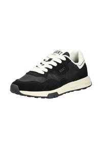 Černé atletické tenisky s krémovými akcenty, svrchní část z semiše a síťoviny, ploché tkaničky, polstrovaný límec, gumová podrážka a logo na jazyku.