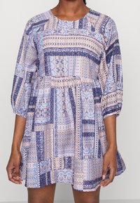 Wielokolorowa sukienka z niebieskimi i brzoskwiniowymi wzorami, okrągłym dekoltem i półdługimi bufkami, wykonana z lekkiego materiału z marszczonym w pasie.