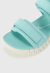 Ανοιχτό μπλε σανδάλι με φαρδιές υφασμάτινες λωρίδες, υφασμένο πέλμα και παχύ λευκό σόλας με μοτίβο κυμάτων. Ρυθμιζόμενος κλεισμός για καλύτερη εφαρμογή.