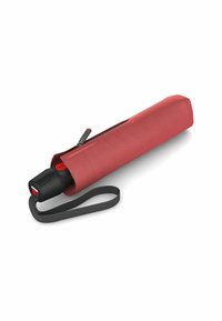Paraguas rojo en un estuche con cremallera. El mango es negro con un botón rojo; cuenta con una correa gris para un fácil transporte.