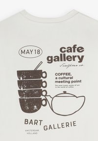 Weißes T-Shirt mit einem Grafikdesign in Dunkelbraun, das gestapelte Kaffeetassen und eine Teekanne zeigt, sowie Textelementen und einem Totenkopf-Icon.