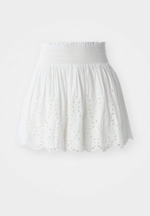Hvit bomullsskjørt med smocket liv, med broderte blomsterutskjæringer langs kanten og en utsvikt silhuett.