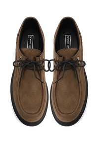 Scarpe in suede marrone con una consistenza liscia, punta tonda, lacci neri e suola in gomma nera. Design minimalista, con una finitura morbida.