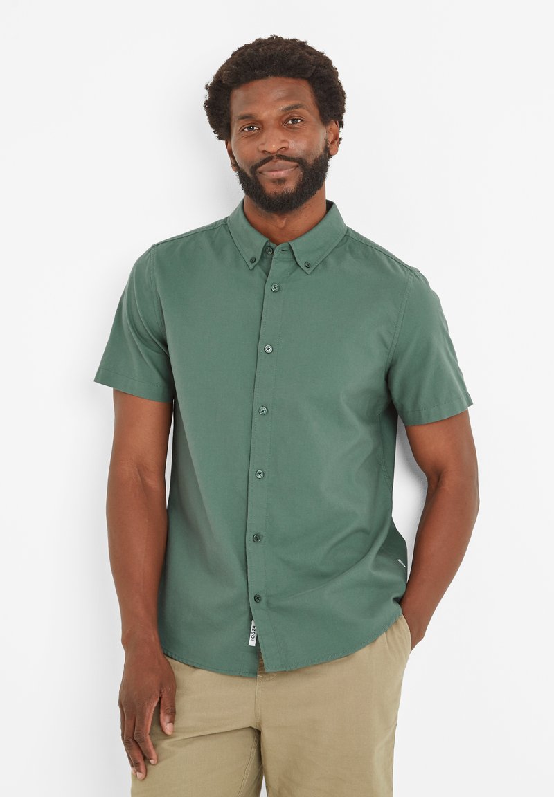 Short-sleeve, button-up shirt in dark green fabric, featuring a classic collar, visible buttons, and a tag at the hem.
