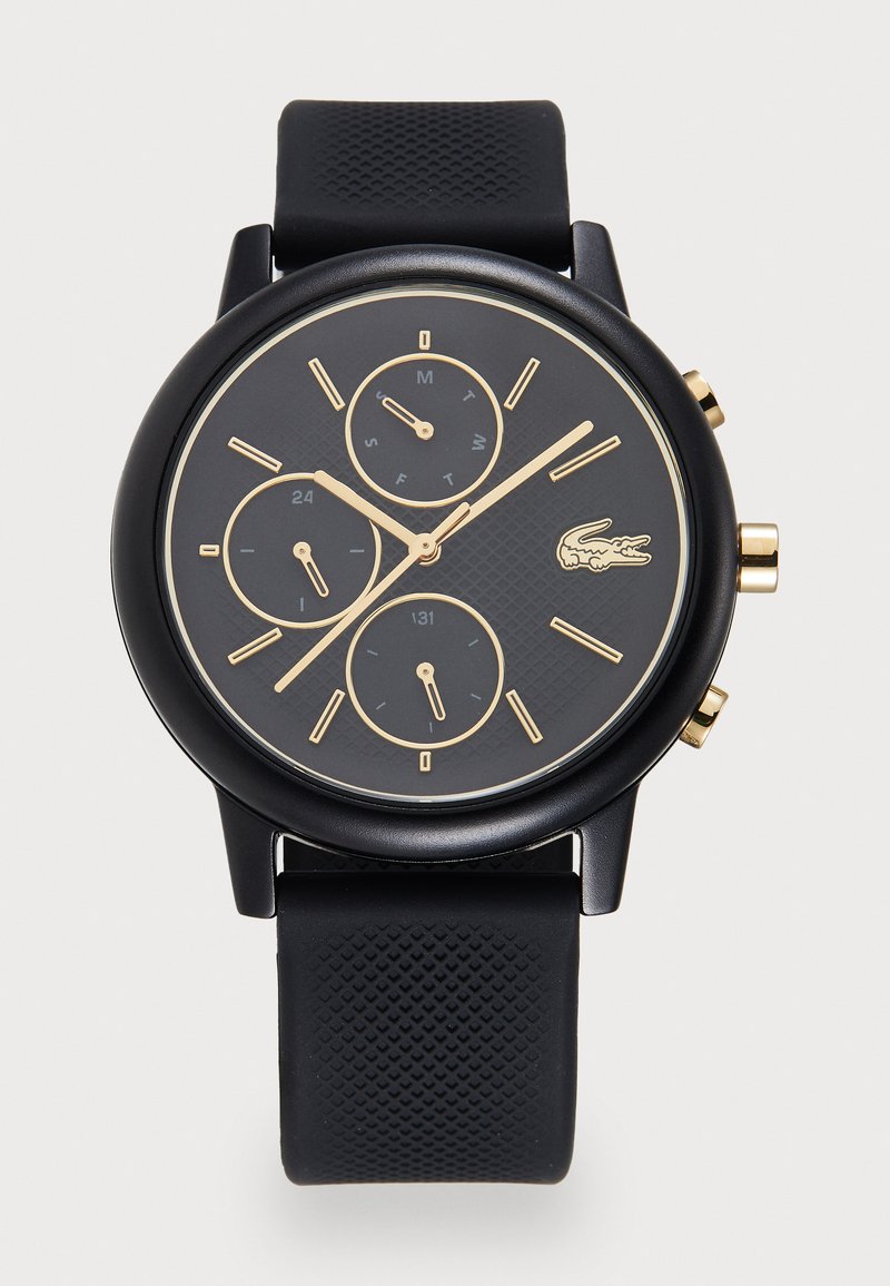 Montre chronographe noire avec un cadran texturé noir, des accents dorés, trois sous-cadrans et un bracelet en caoutchouc avec un motif en diamant.