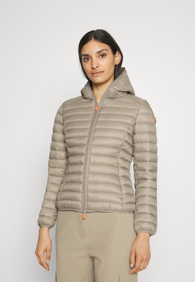Lichtbeige pufferjack met horizontaal gestikt ontwerp, ritssluiting met oranje accent en aangehechte capuchon. Zachte, gladde textuur.