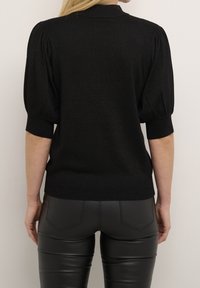 Sort strikket pullover med høj krave og puffede korte ærmer; tætsiddende design fremhæver formen. Blød tekstur med en let glans.