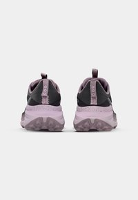 Zapatillas deportivas con una parte superior negra y lavanda, cuello acolchado, suela texturizada y lengüeta en el talón. Presenta una media suela moteada.