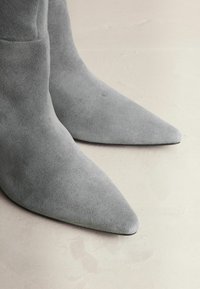 Gray suede ankle boots with a pointed toe design and smooth texture, positioned on a light surface. No visible hardware or accents.