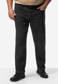 Czarne dżinsy o luźnym kroju, z prostymi nogawkami, subtelną teksturą i podwiniętymi mankietami, połączone z czarnymi butami sportowymi.