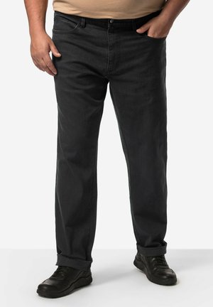 Jeans en denim noir avec une coupe décontractée, présentant une jambe droite, une texture subtile et des ourlets retroussés, associés à des chaussures de sport noires.