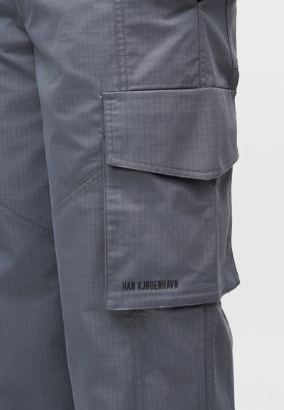 Γκρι cargo παντελόνια με υφή υφάσματος, που διαθέτουν πλαϊνή τσέπη και τυπωμένο λογότυπο "HAN KJØBENHAVN" κοντά στο τελείωμα.