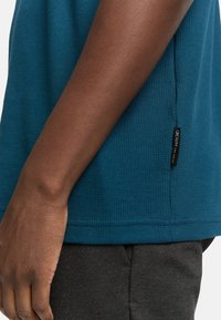 Téglás textúrájú, rövid ujjú ing bordázott mintával, oldalsó címkével, sötét szürke nadrággal párosítva.