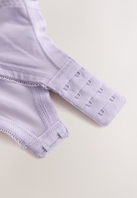 Close-up of lavender bra hook-and-eye closure with three rows of hooks and two columns of eyes on mesh fabric.