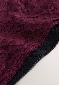 Bordeauxrode kantstof met bloemenpatronen, gelaagd over zwarte kant, met gegolfde randen en fijne details. Soepele textuur.