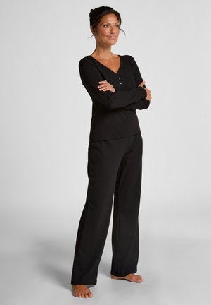 Completo di abbigliamento da casa nero, composto da una maglia a maniche lunghe con scollatura a V e dettaglio di bottoni, abbinato a pantaloni larghi, realizzato in tessuto morbido.