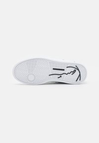 Hvid sneaker sål med tekstureret gummi, der har et fiskebensmønster og et sort abstrakt design. Glat overflade med et cirkulært accent.