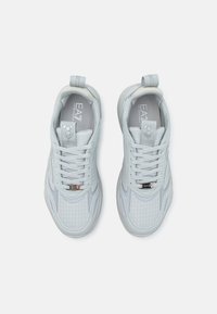 Light gray athletic shoes with a textured mesh upper, lace-up design, and padded collar. Features a subtle logo on the tongue and accents.