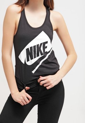 Zwart tanktop met een wit Nike-logo en -ontwerp. De stof is glad en heeft een racerback-stijl. Gecombineerd met donkere jeans.