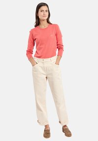 Camicia a maniche lunghe corallo, pantaloni a vita alta crema e scarpe slip-on con stampa leopardata. Vestibilità casual con tasche e maniche arrotolate.