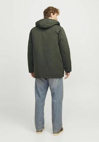 Grüne gepolsterte Jacke mit Kapuze, mit geradem Schnitt und strukturiertem Stoff. Trägt man mit hellblauen Jeans und braunen Schuhen.