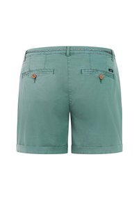 Pantalones cortos verdes hechos a medida con dobladillos enrollados, dos bolsillos de ojal traseros con botones y una cinturilla interior con estampado visible en la parte superior.
