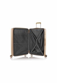 Valise rigide beige avec une poignée télescopique, intérieur gris, sangles croisées et compartiments fermés par zip. Roues à roulement fluide.
