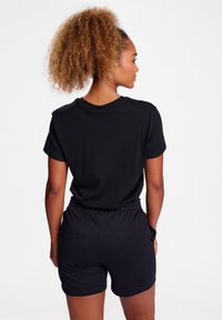 Schwarzes T-Shirt mit kurzen Ärmeln und Shorts aus weichem Material, mit lockerer Passform und elastischem Bund, von hinten betrachtet.