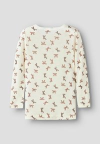 Chemise à manches longues en tissu crème avec un motif répété de nœuds marron et beige. Encolure ras du cou et coupe standard.