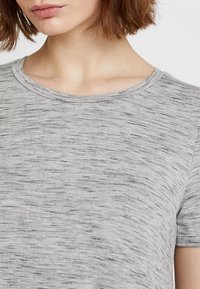 T-shirt gris mélangé à manches courtes avec un col rond, présentant une texture de tissu douce et des motifs horizontaux subtils.