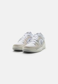 Nízké tenisky z bílé kůže s šedými semišovými akcenty. Mají perforované panely na špičce, bílé tkaničky a strukturovanou podešev.