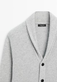 Ljust grått ribbat kCardigan med sjalkrage, som har tre svarta knappar och en tagg som säger "Massimo Dutti." Mjuk, texturerad tyg.