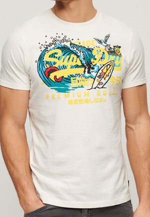 Weißes Baumwoll-T-Shirt mit einem farbenfrohen Grafikdesign aus Wellen, einem Surfbrett und Text in Gelb und Blau. Kurze Ärmel und Rundhalsausschnitt.