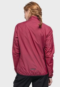 Rote, leichte Jacke mit glatter Textur, hohem Kragen und elastischen Bündchen. Verfügt über eine taillierte Passform und einen reflektierenden Akzent auf der Rückseite.