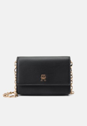 Black faux leather crossbody bag with a gold chain strap, featuring a magnetic flap closure and embossed logo detail on front.