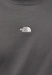 Γκρι φούτερ με ριμπ λαιμόκοψη· διαθέτει ένα μικρό λευκό κεντητό λογότυπο της "The North Face" στην αριστερή περιοχή του στήθους. Μαλακή υφή υφάσματος.