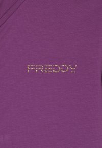 Camicetta di cotone viola con un logo testurizzato "FREDDY" realizzato in perline dorate sul davanti. Tessuto liscio con un design aderente.