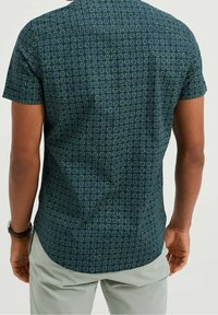 Kortärmad skjorta i marinblått tyg med ett geometriskt grönt mönster; rundad fåll och detaljer med knäppt krage.