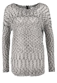 Pull-over à manches longues en maille, tricoté avec un fil chiné noir et blanc dans un motif texturé à mailles ouvertes, avec un col rond et une fermeture éclair dans le dos.